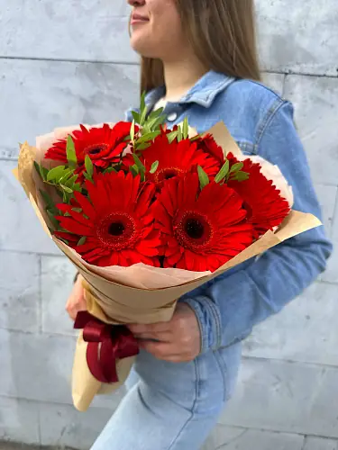 На фото №2 Букет живых цветов из 7 Красных гербер с зеленью в дизайнерской упаковке