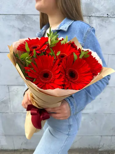 На фото №4 Букет живых цветов из 7 Красных гербер с зеленью в дизайнерской упаковке